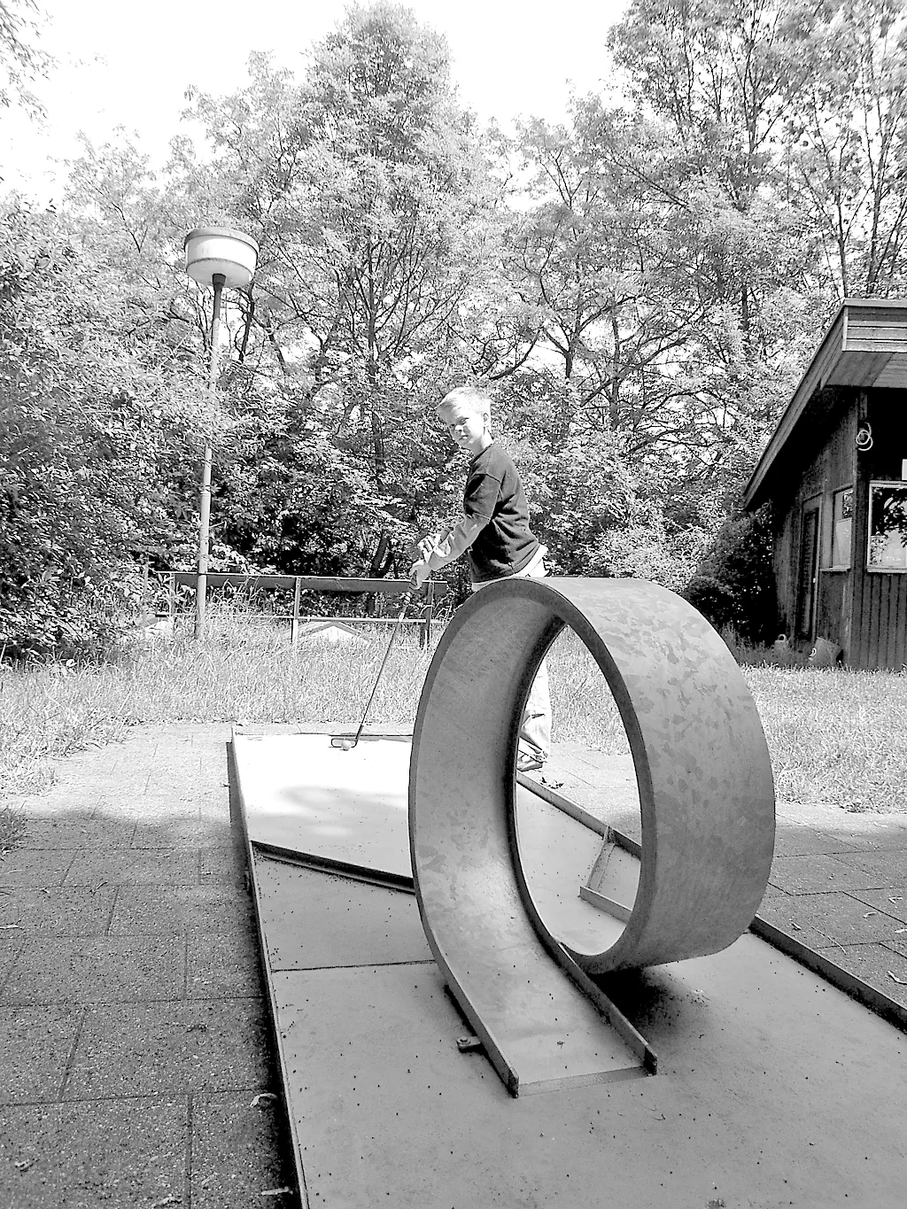 Historische Schwarz-Weiß-Aufnahme einer Minigolfbahn mit Looping und einem Spieler