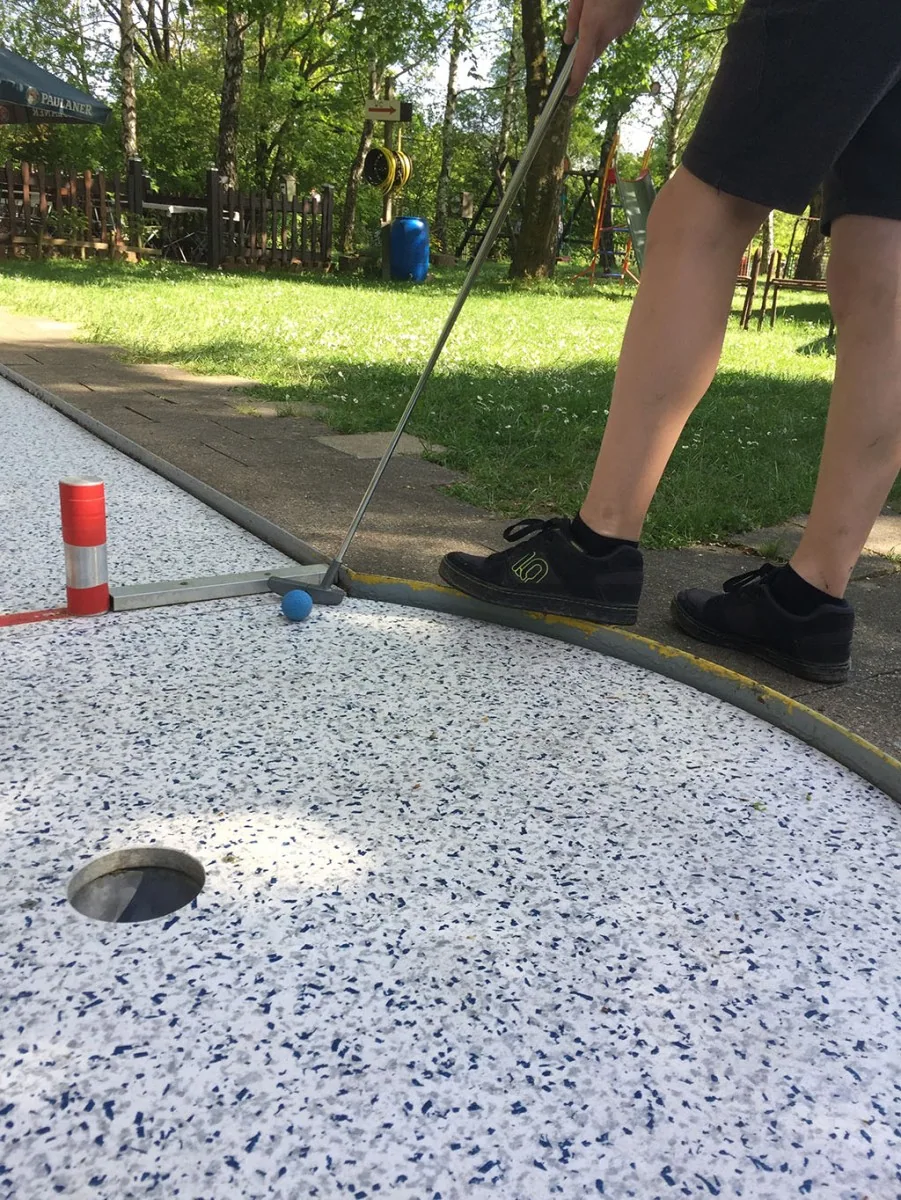 Schläger und Ball auf einer Minigolfbahn